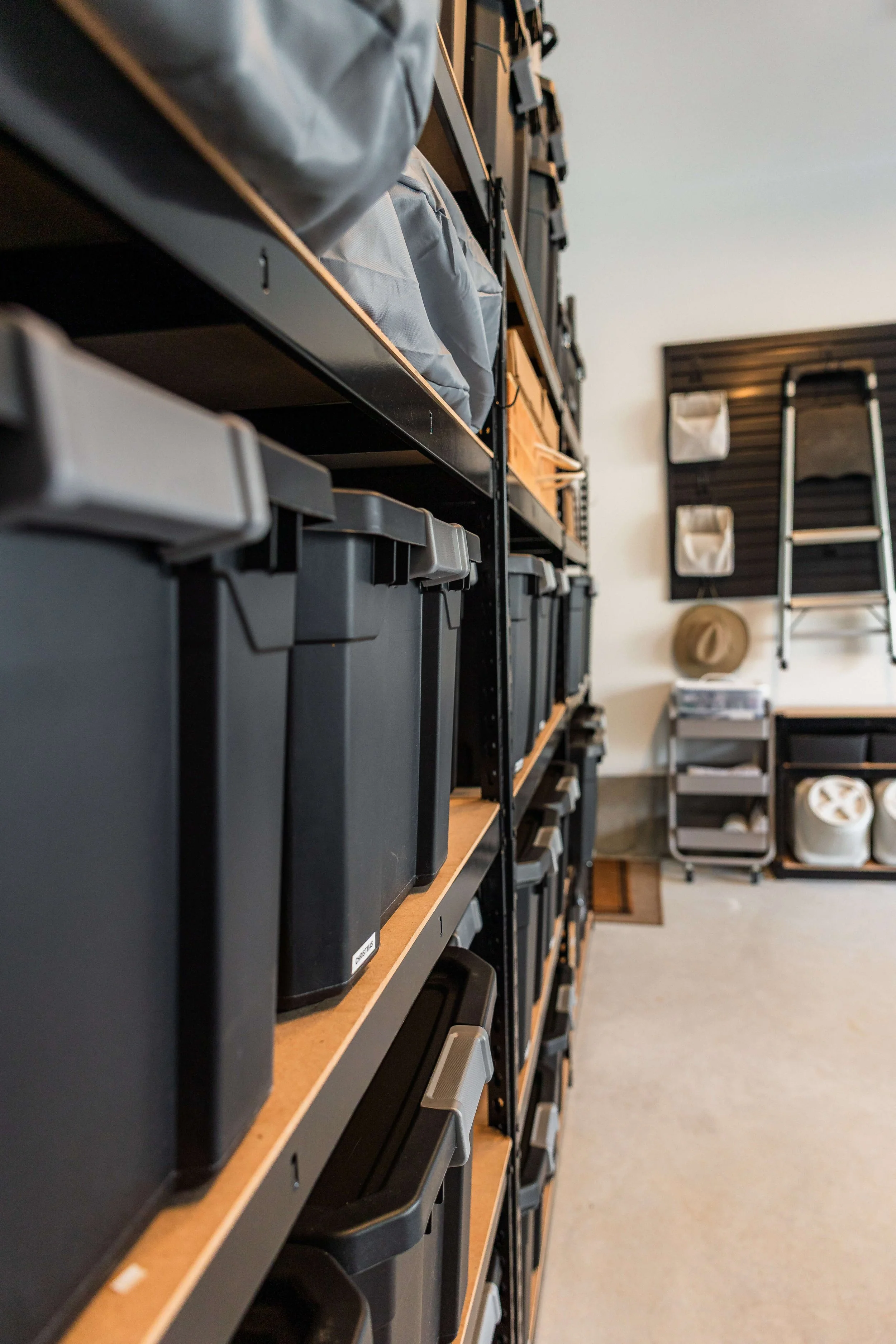 abeled black storage bins arranged on garage shelves for organized storage