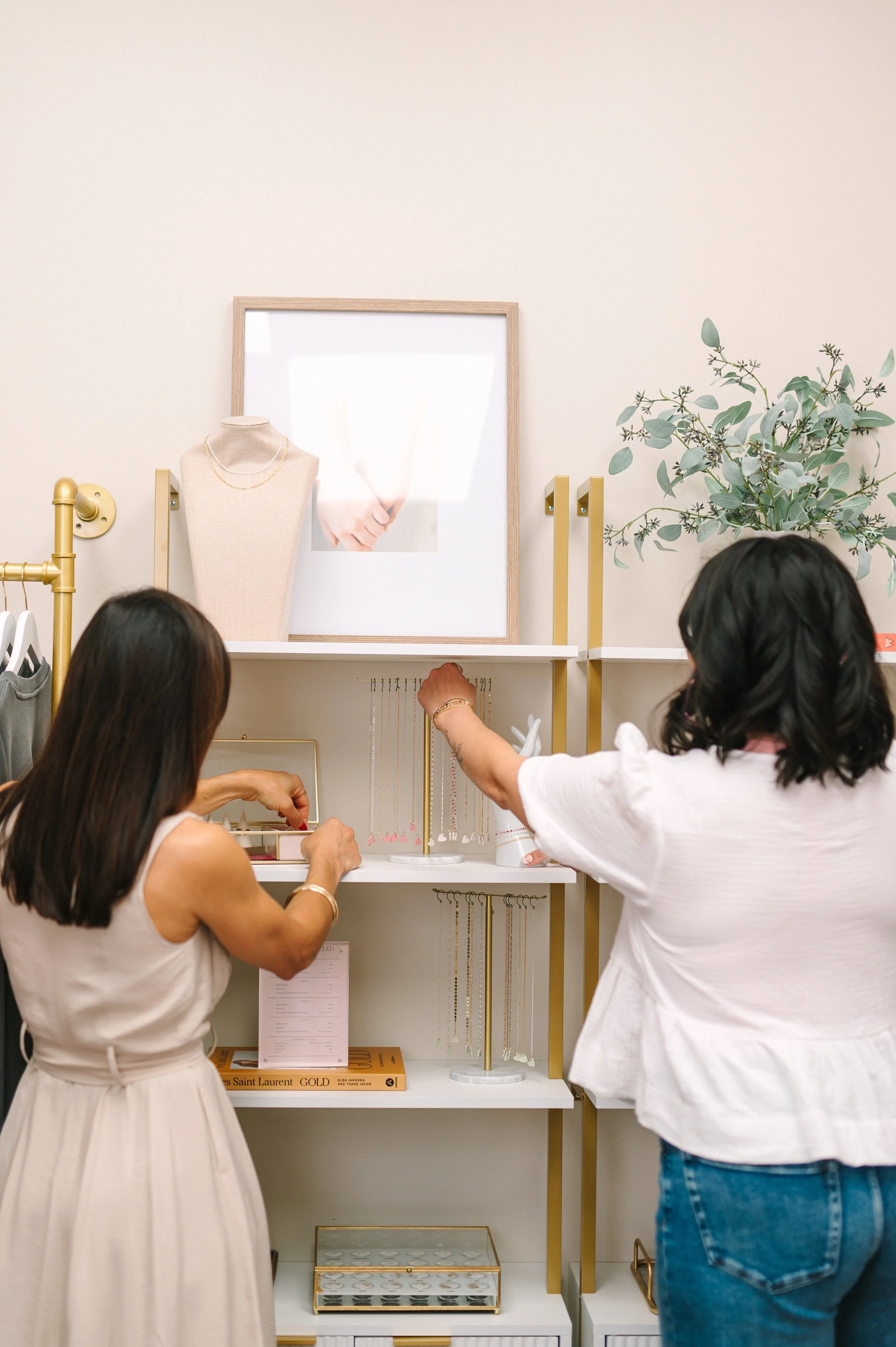 Interior designer collaborating with store owner while styling retail shelving for optimal merchandising.