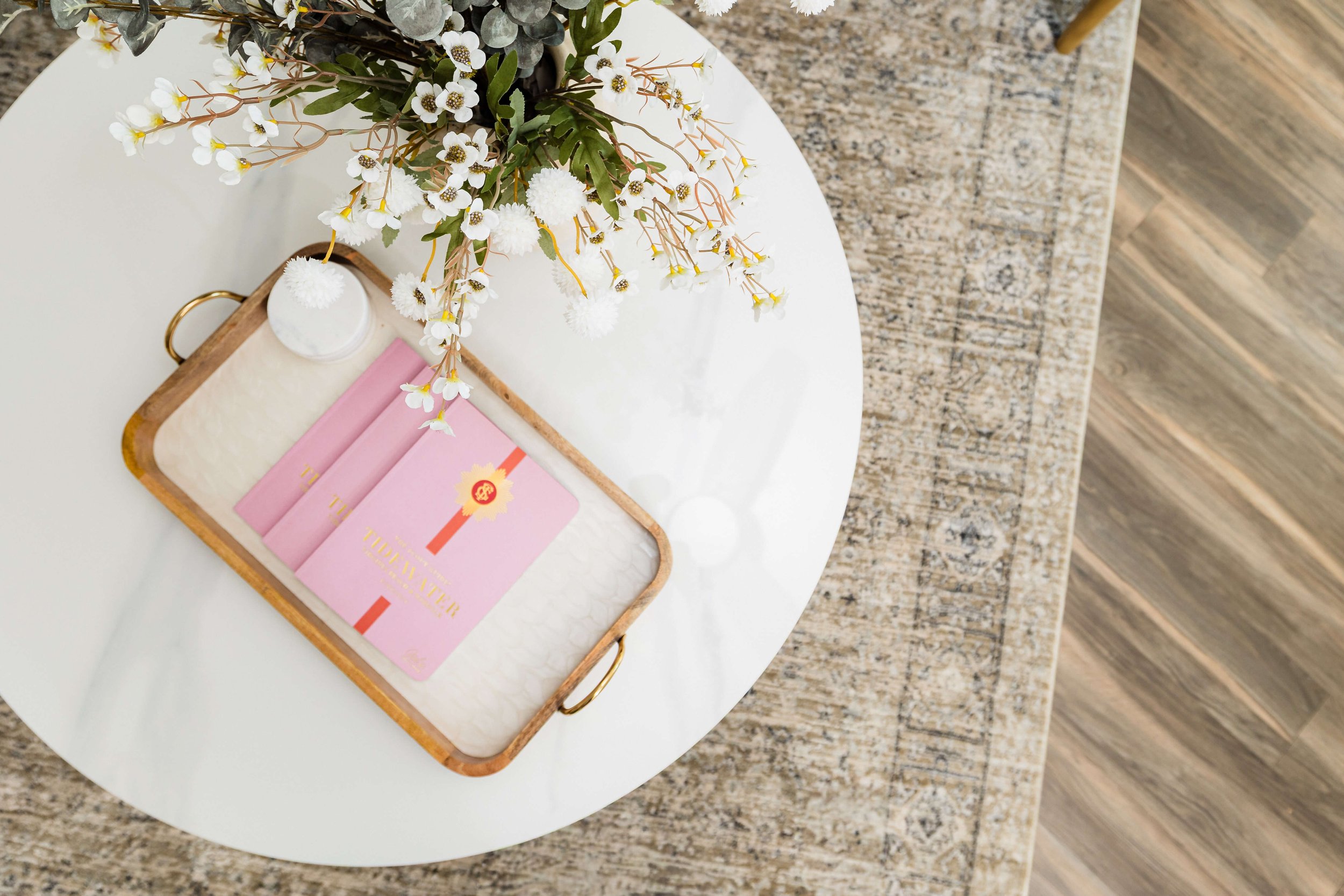 Overview of a styled coastal coffee table featuring a tray, floral arrangement, and the Tidewater Scout Guide.