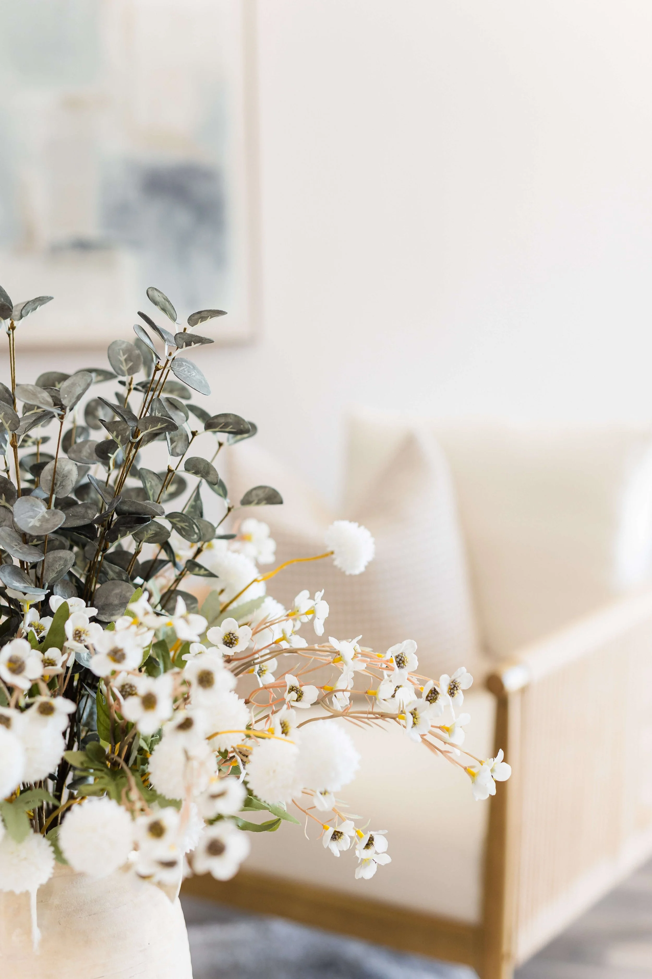Close-up detail of coastal florals styled beside an accent chair in a modern, hotel-inspired living room.