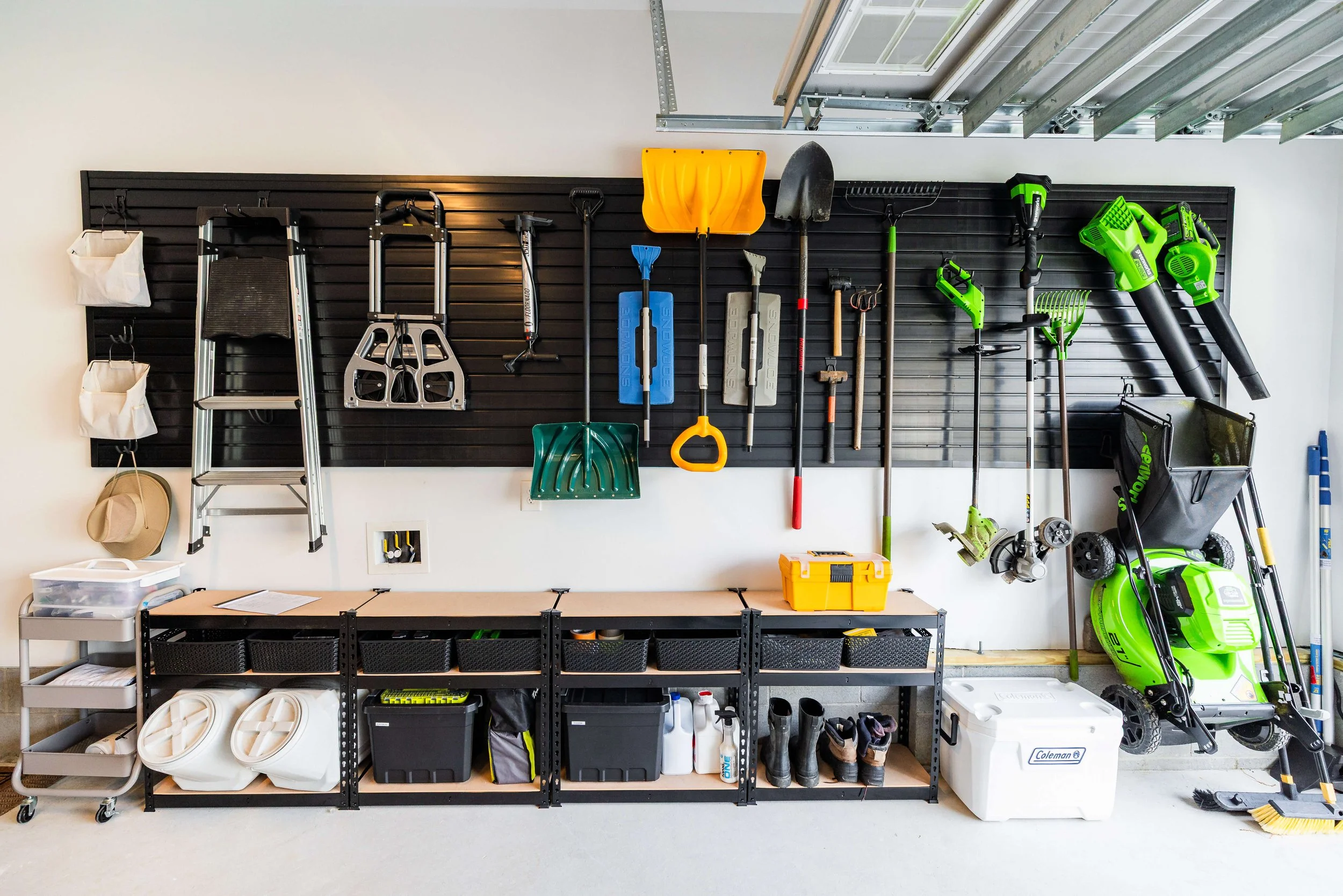 Garage slatwall system organizing yard tools like rakes, shovels, and hoses in a Virginia Beach home.