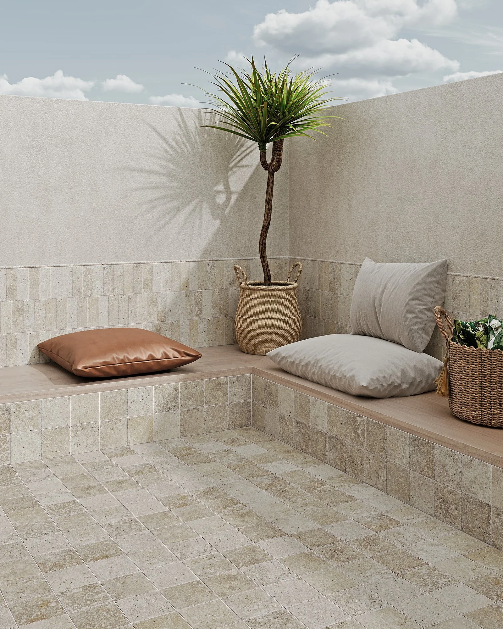 Corner of an outdoor patio with beige tiled floor, beige walls, a tall potted plant with a twisted trunk, two pillows, and a wicker basket.