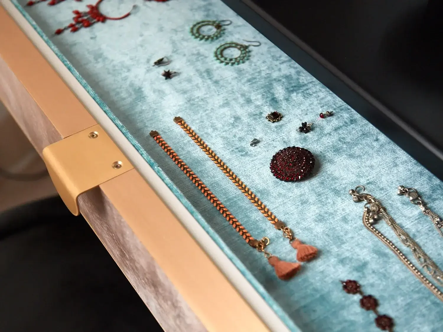 Jewelry display case with necklaces, earrings, and brooches arranged on a velvet surface.