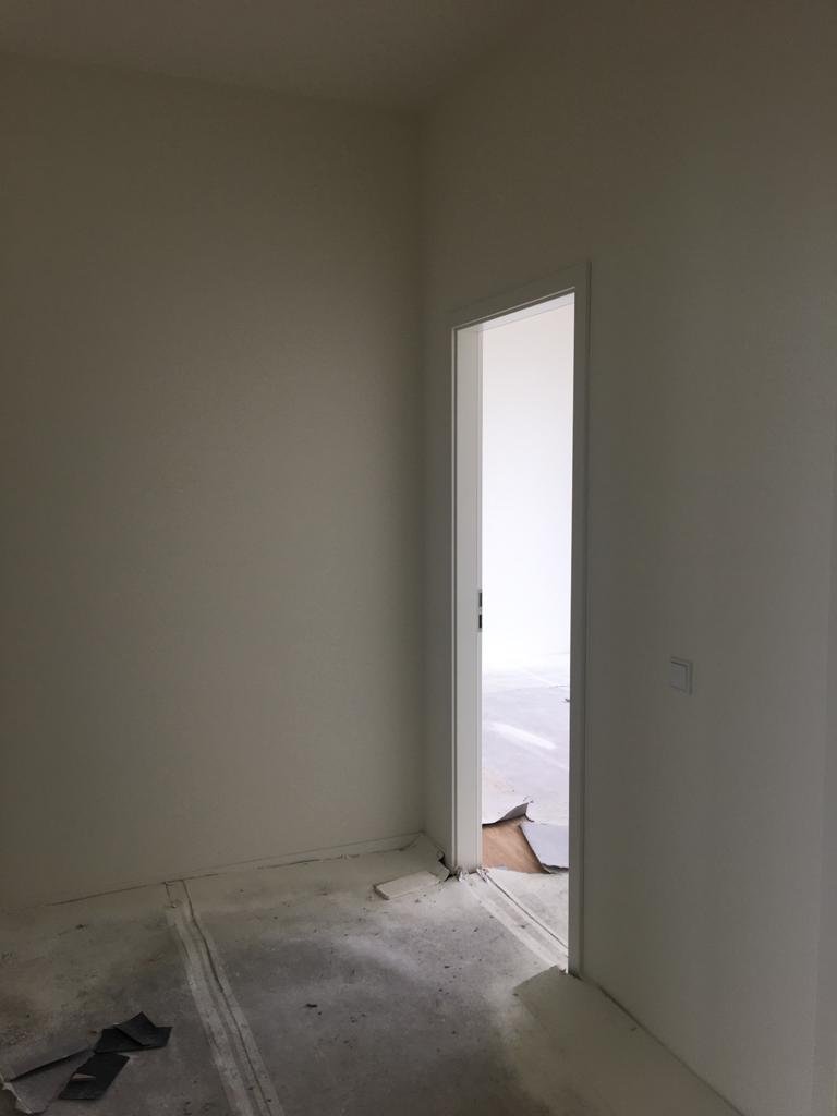 Empty unfinished room with white walls and a partially installed door.