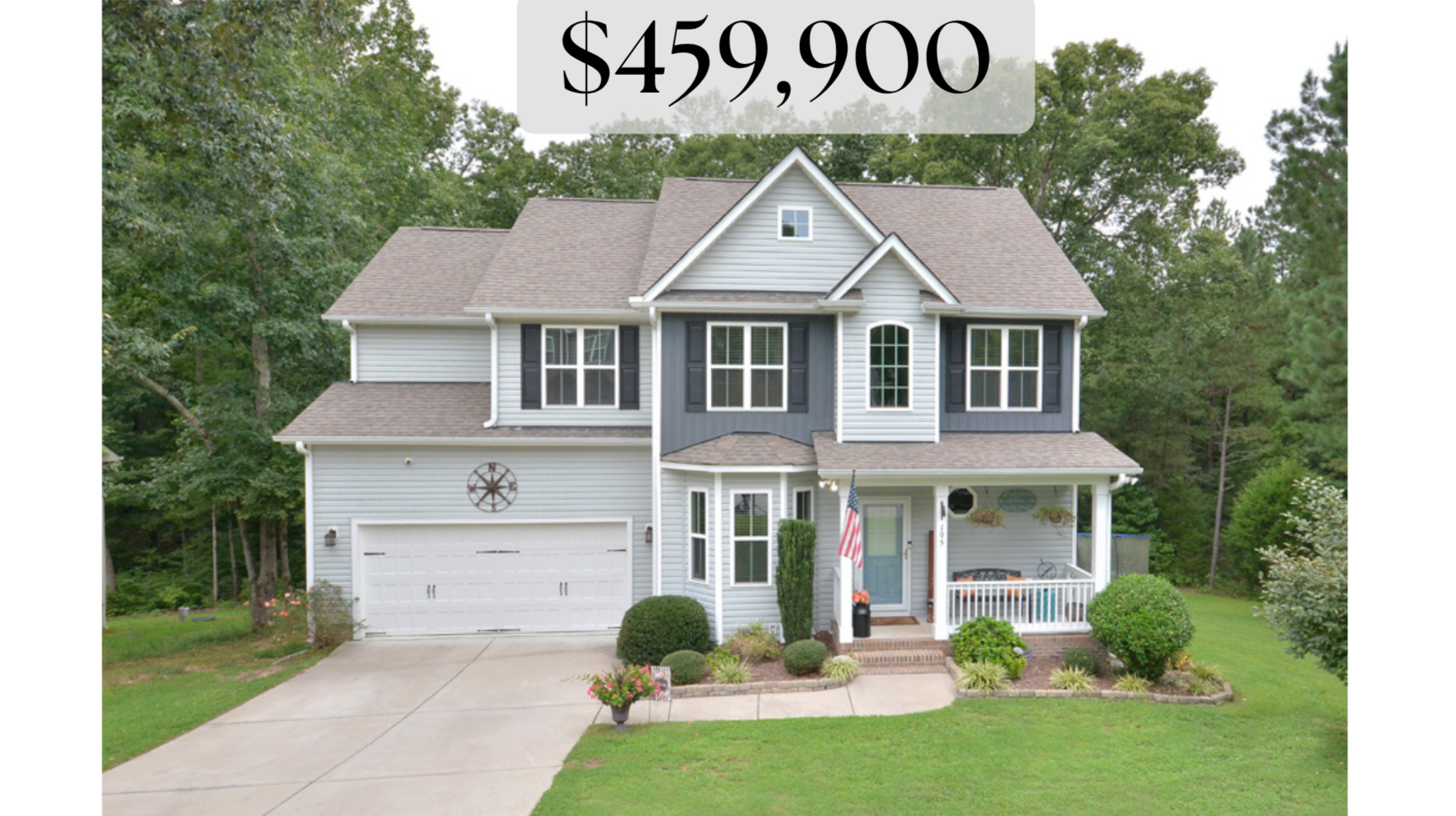 Front view of a two-story suburban house with a gray and blue exterior, white trim, a two-car garage, and a small front porch adorned with plants and an American flag.