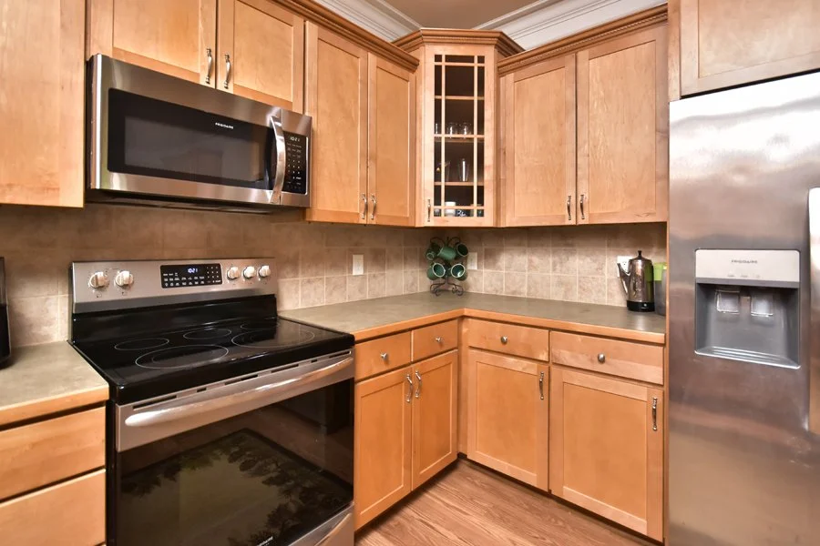 Kitchen with wooden cabinets, a stainless steel microwave, electric stove, and a side-by-side refrigerator with water and ice dispenser.