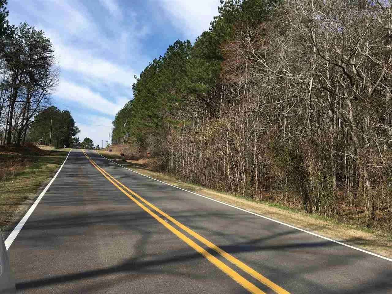 A rural road with double yellow lines, trees on both sides, and a partly cloudy sky. A red banner with white text reading 'UNDER CONTRACT' overlays the bottom of the image.