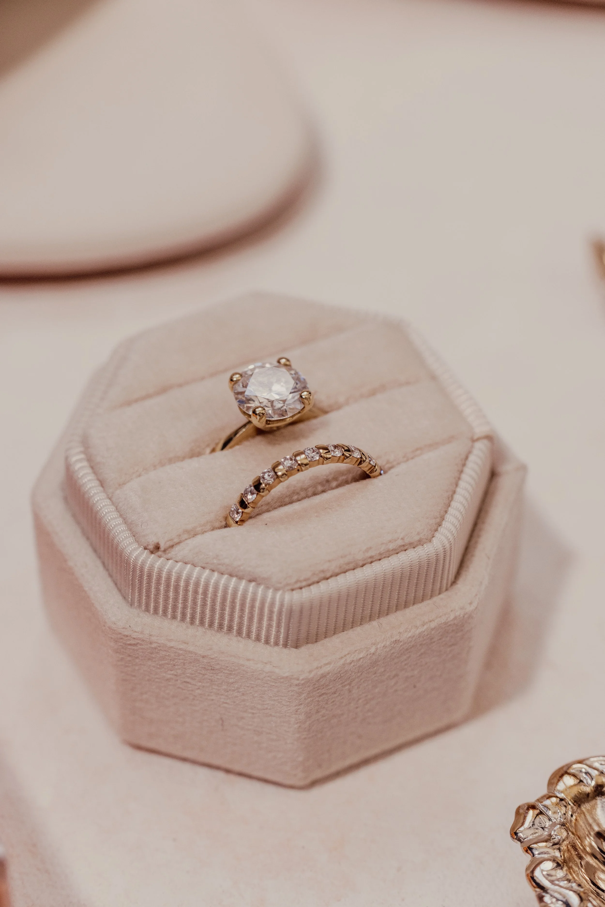 Two elegant rings displayed in a soft, white velvet jewelry box, featuring a large solitaire diamond and a band with smaller diamonds.