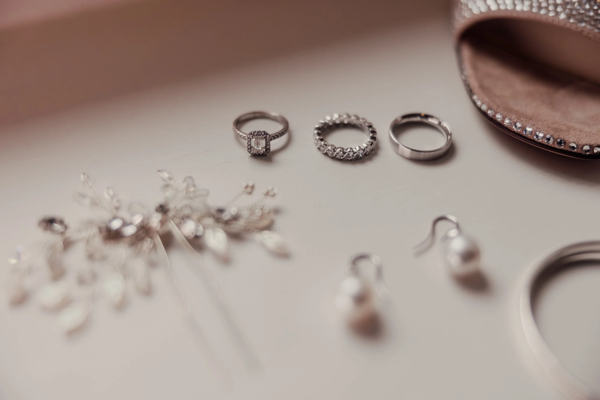 Assorted silver jewelry including rings, earrings, and a headpiece on a light surface.