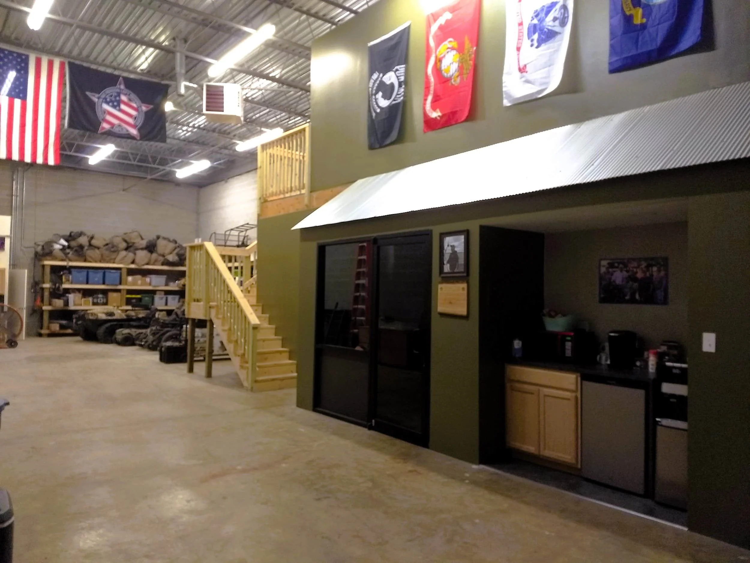 Interior of the NPLB Outdoors facility featuring military branch flags, adaptive hunting equipment, and workspace used to support veteran outdoor programs.