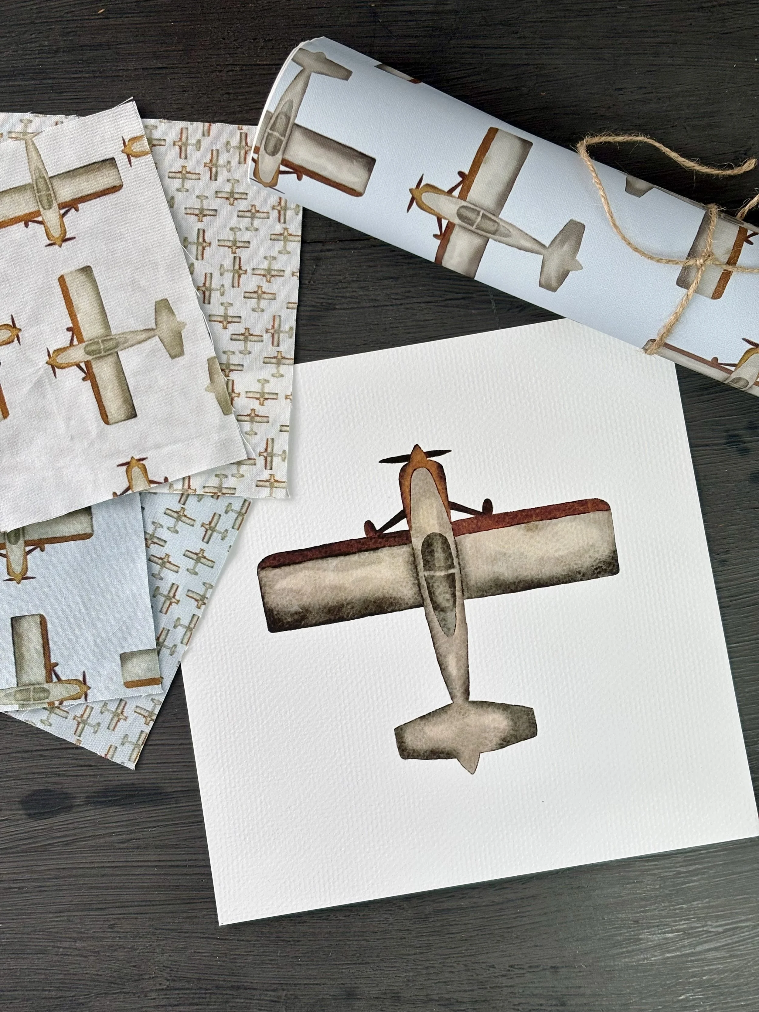 Watercolor painting of a vintage Van's aircraft on watercolour paper, surrounded by wallpaper and fabric samples using the watercolour painting.