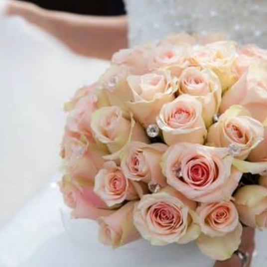 A bouquet of pale pink and cream roses with wedding rings among the flowers.