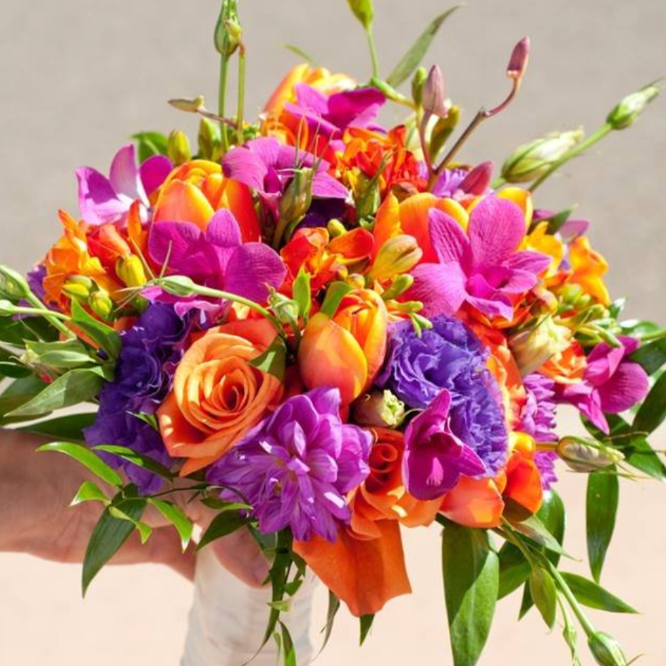 Colorful bouquet of pink, orange, purple, and red flowers with green leaves.