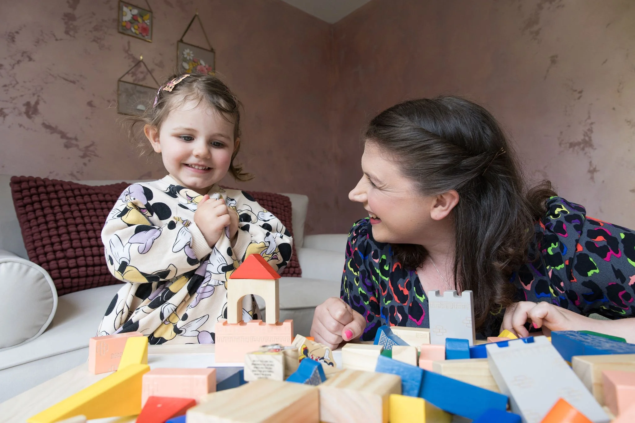 Ed psych smiling and a pleased child who has build a tower from blocks, in an exercise to support there learning a development