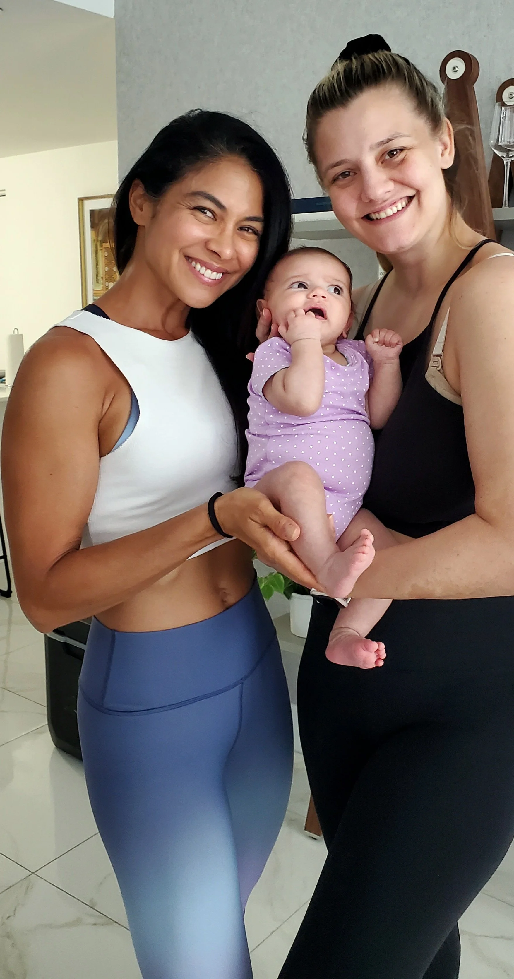 Mom & baby. New mother holds her newborn after birth besides personal trainer Lyen Wong during a Postpartum recovery training session.
