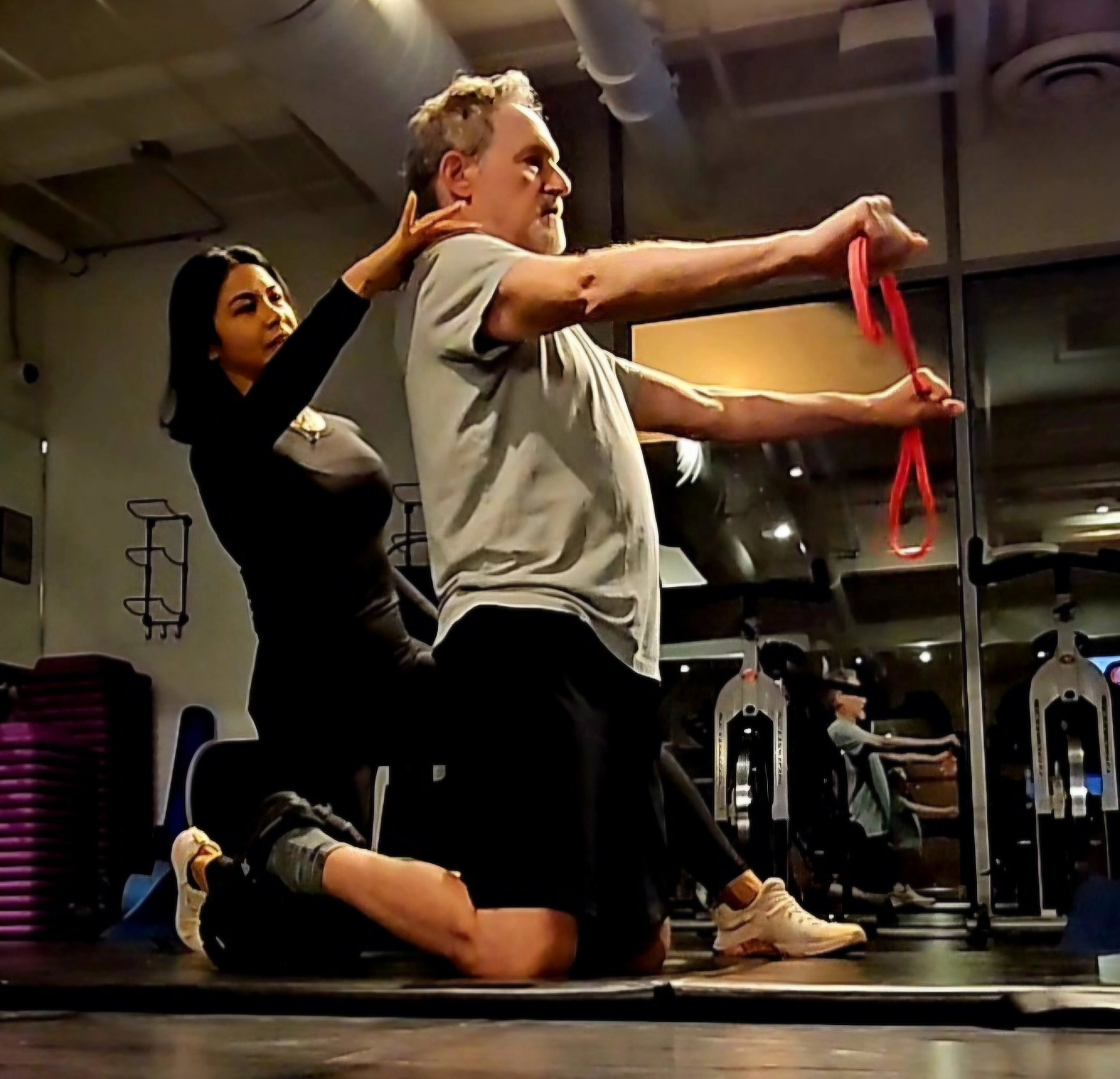 Adult over 40 training  in a fitness studio or gym training doing strength training for  healthy aging and longevity with Lyen Wong using a resistance band