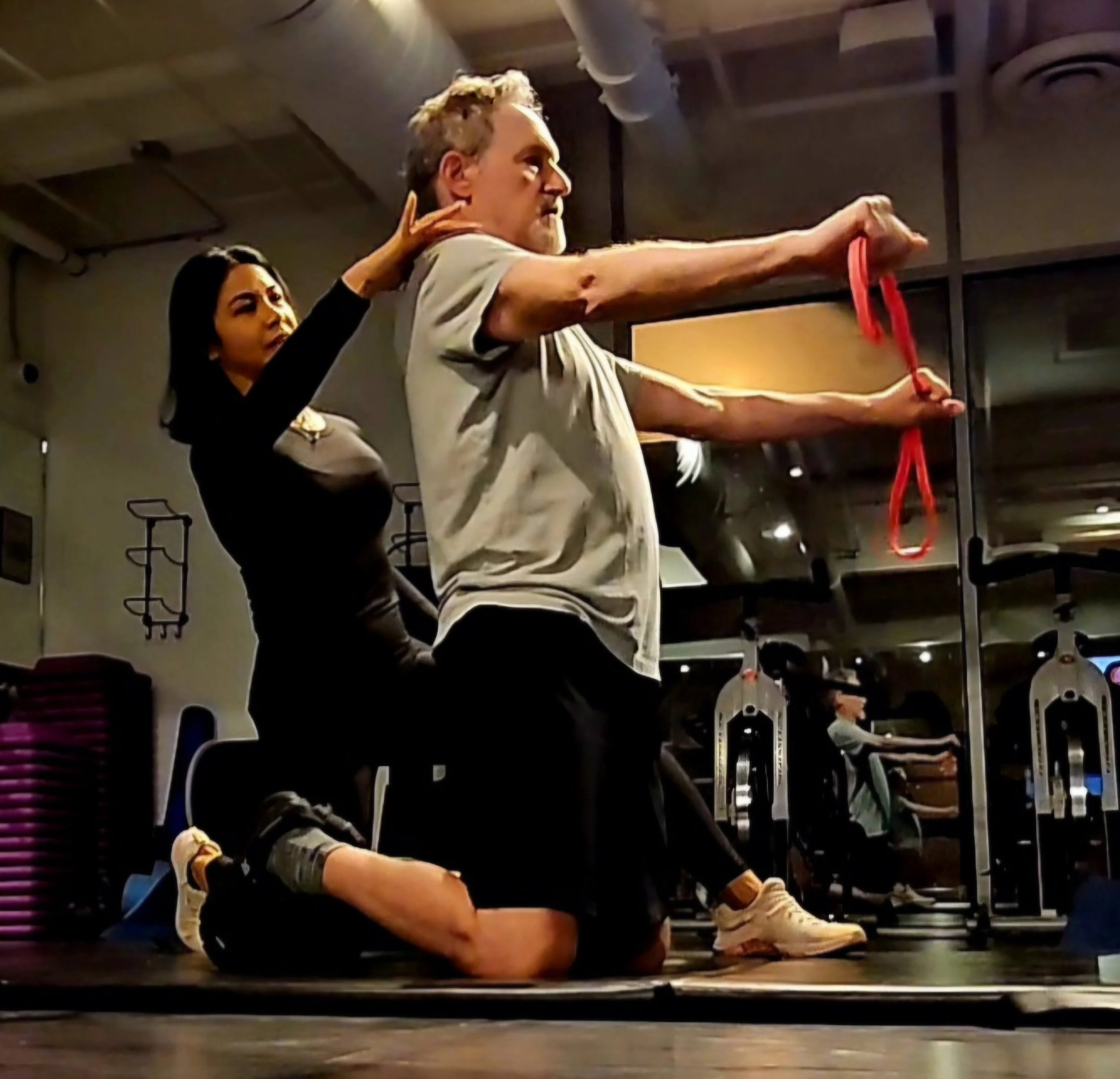 Adult over 40 training  in a fitness studio or gym training doing strength training for  healthy aging and longevity with Lyen Wong using a resistance band