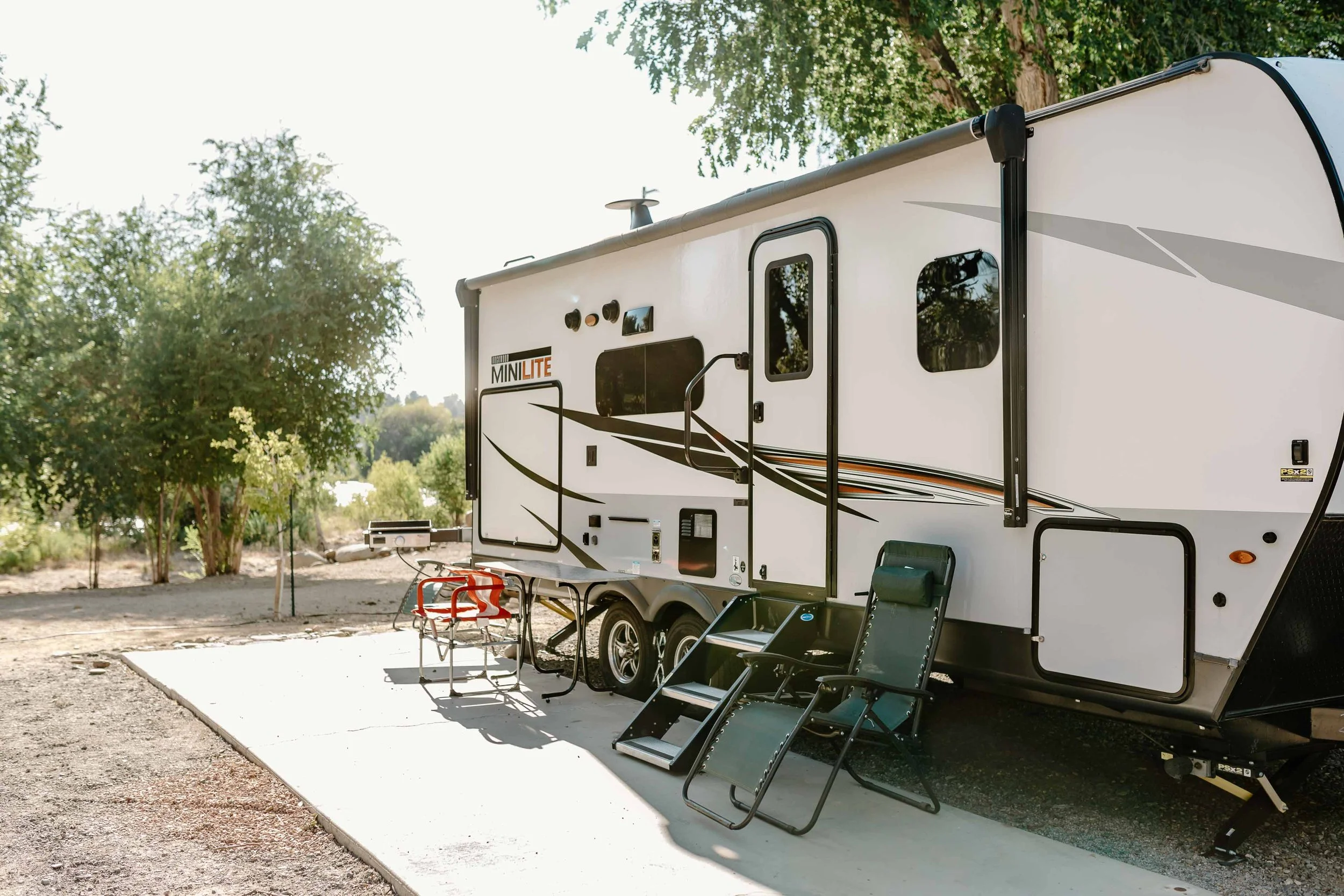 an rv parked by a cement patio with chairs.jpg