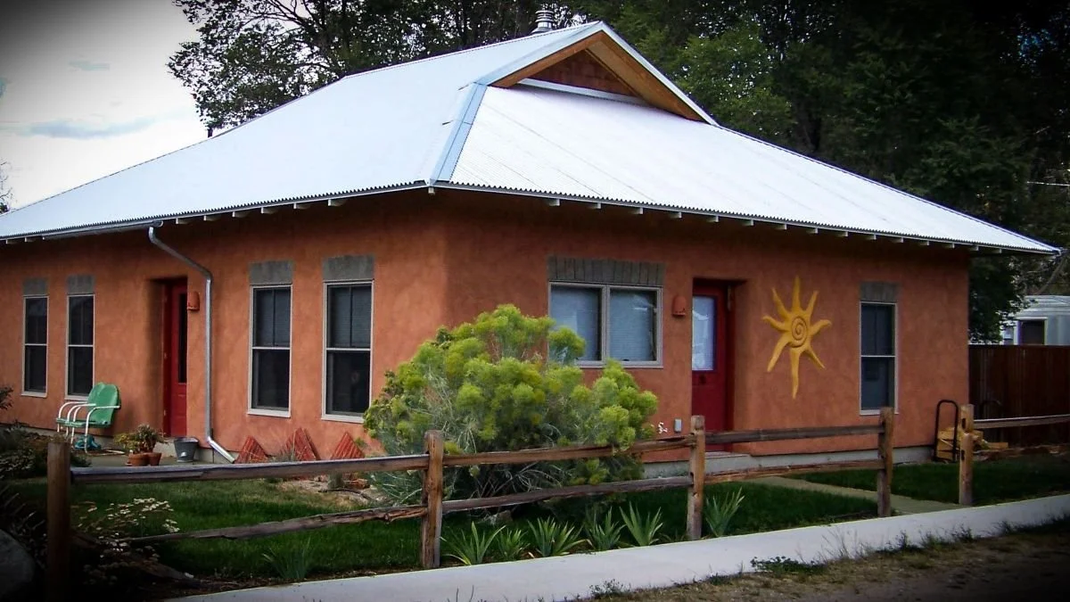 Exterior of a straw bale house exibiting it's beautiful red pigmented lime finish coat.