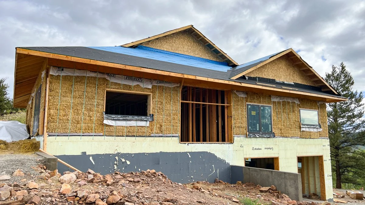 Under construction straw bale home sitting on a significant foaunation due to a sloped site.
