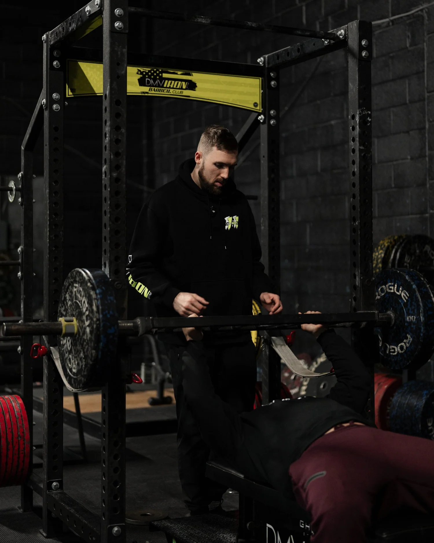Nick Ridpath coaching an athlete through a barbell press in the rack