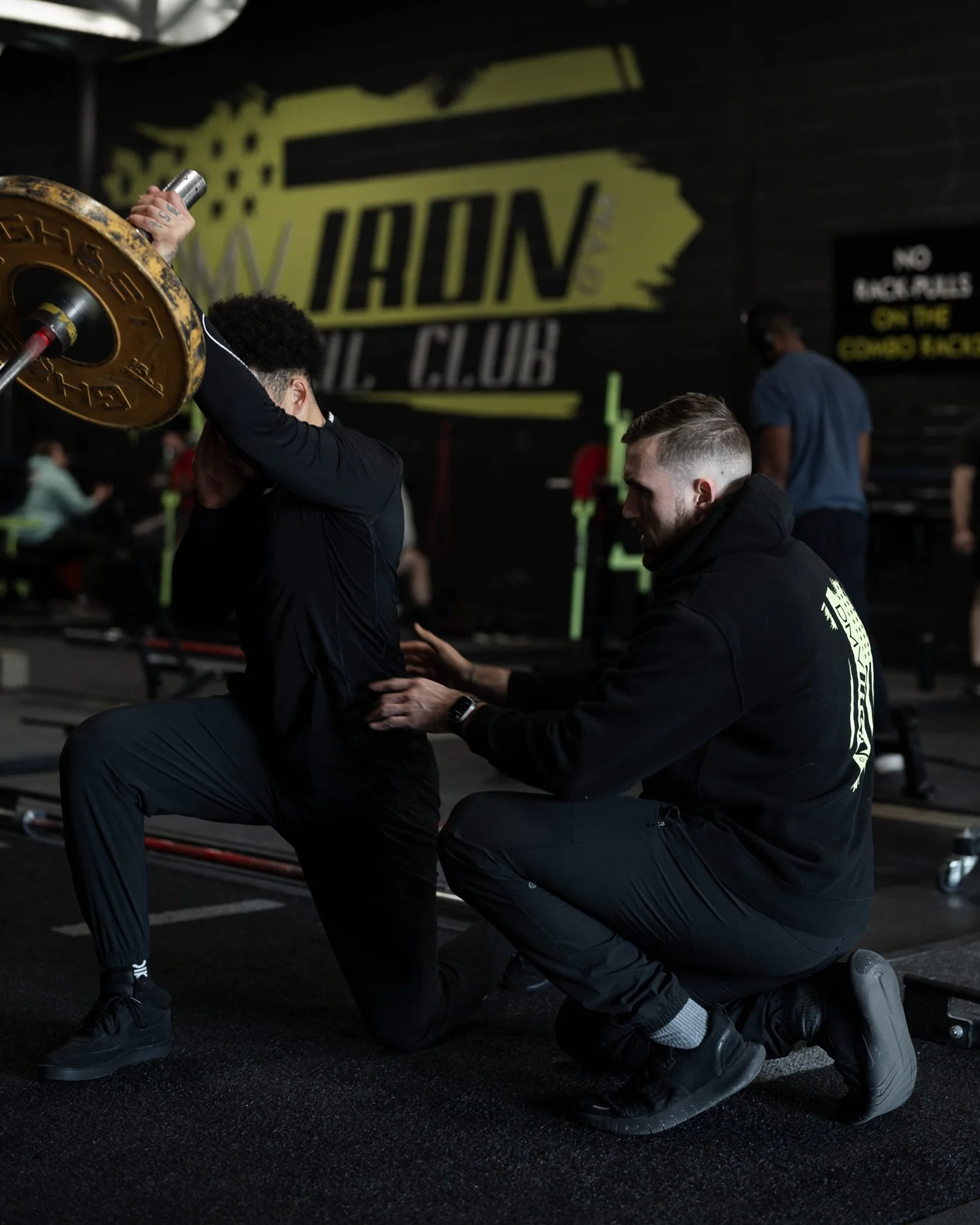 Nick Ridpath giving hands-on cues during a half-kneeling landmine press