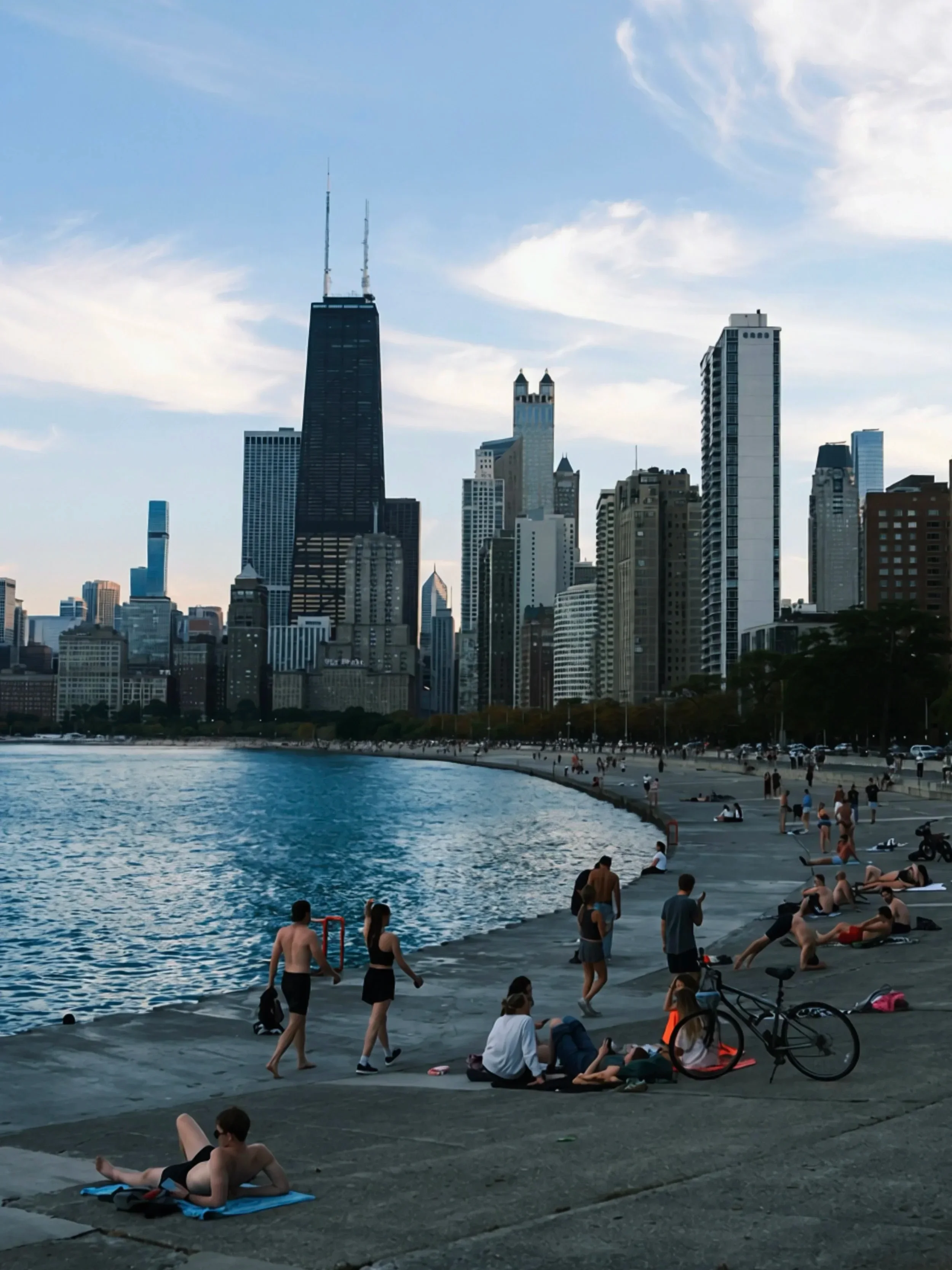 People sitting on the lakefront steps with the skyline behind