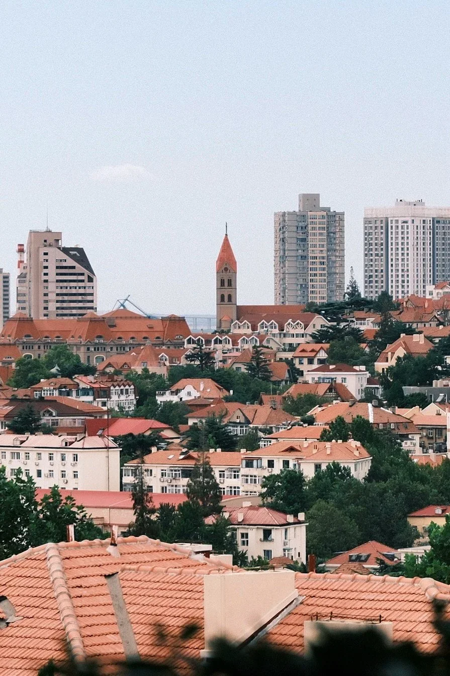 Red-tiled roofs climbing the hill, with a church spire and newer towers behind