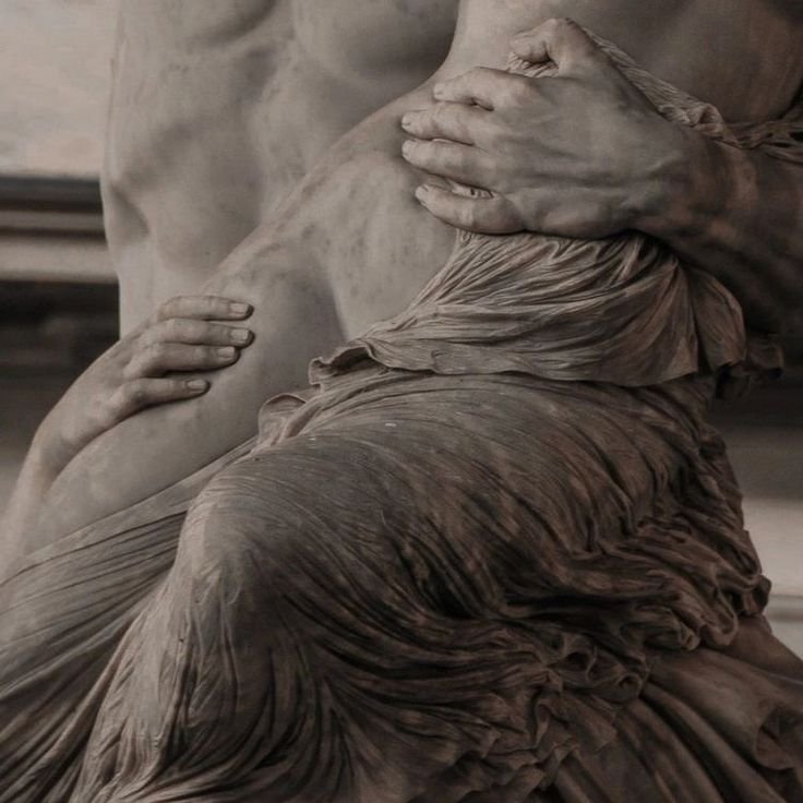 Close-up of a sculpted marble statue depicting two intertwined figures with detailed drapery and hands. Vast Leaf