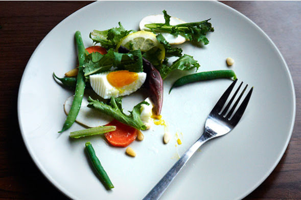 A plate with green vegetables, a boiled egg, and a fork