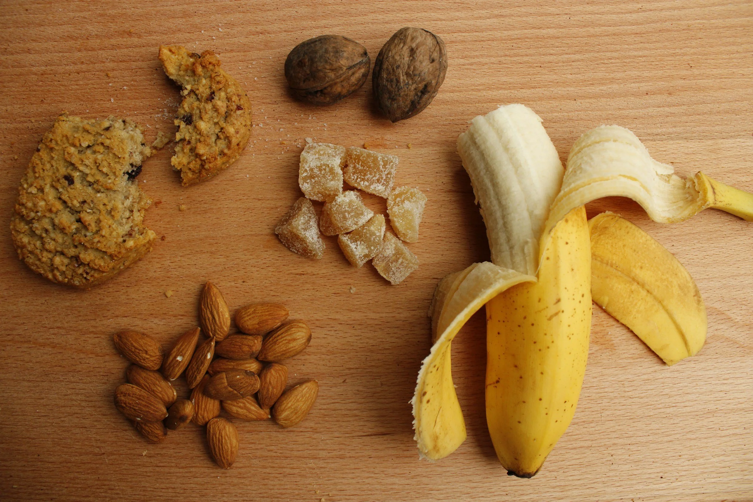 An assortment of food on a table, including a half-peeled banana, dried fruits, and nuts