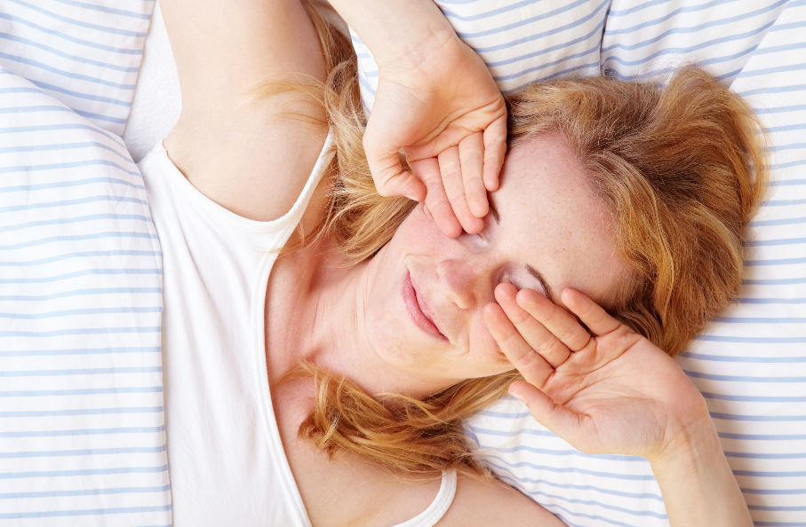 A woman lying in bed, rubbing her eyes