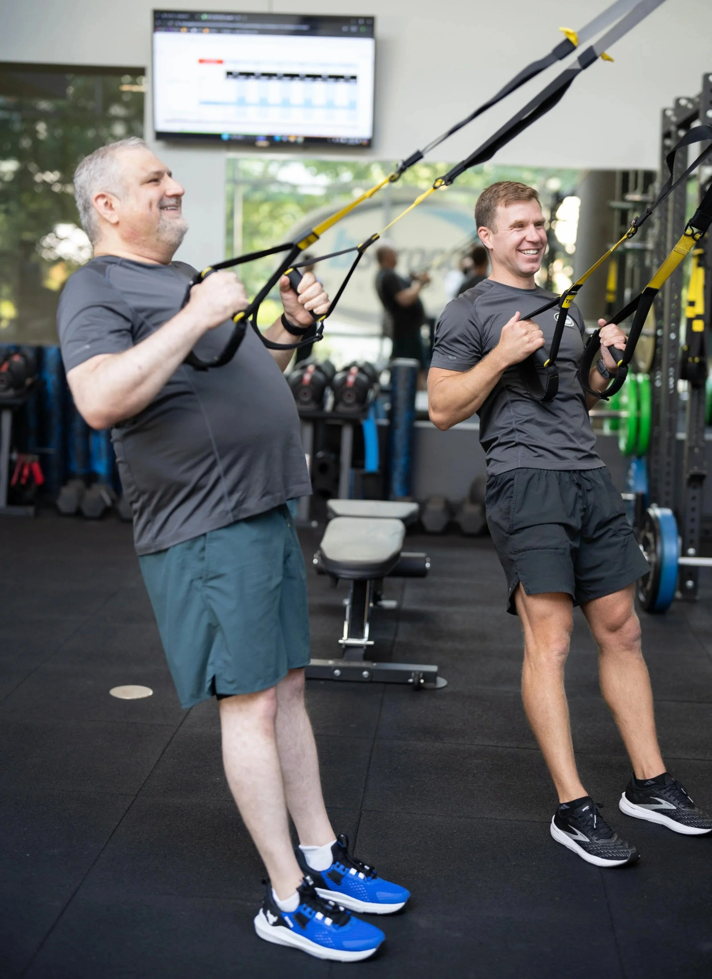 A bStrong member performs a rowing exercise, following the instructions of his personal trainer.