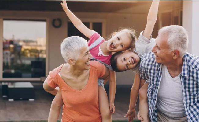 A mature couple playing with two young kids, presumably grandkids
