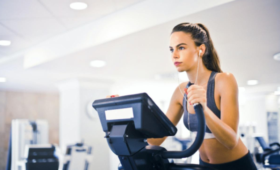 A woman wearing headphones on an elliptical