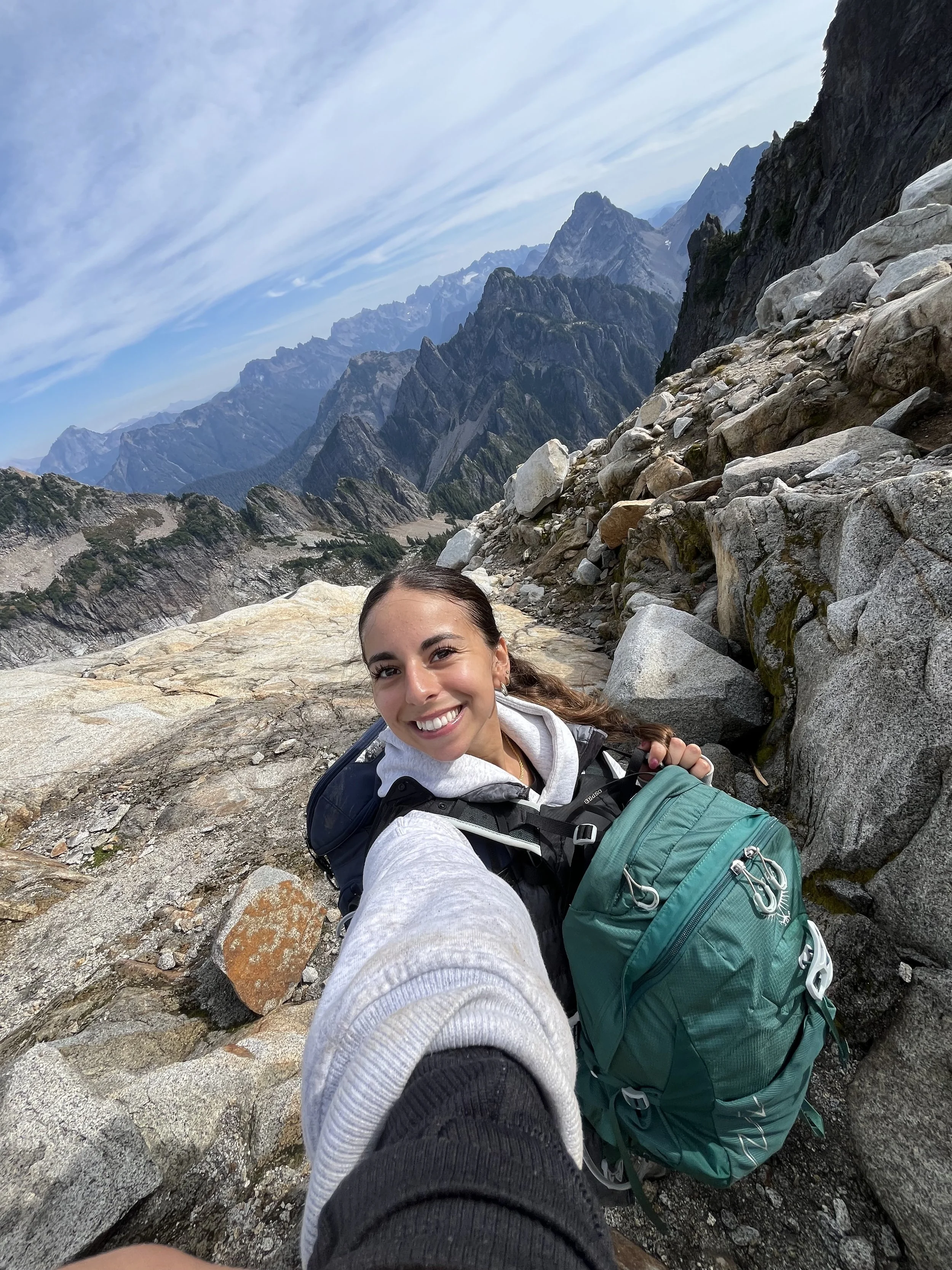 bStrong Coach Hayley taking a selfie holding a backpack with large mountains in the background