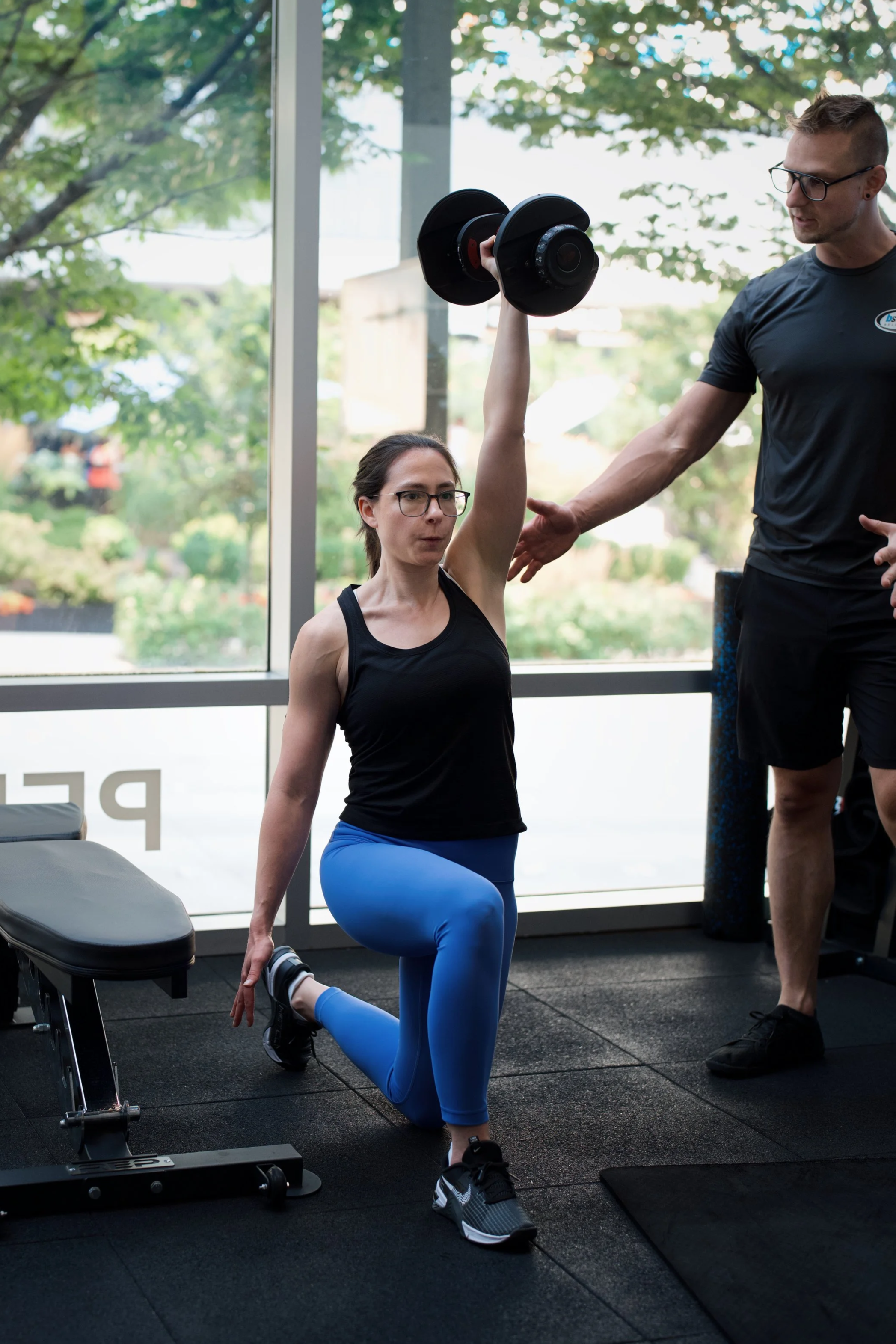 bStrong coach helping a member through a dumbbell strength exercise during a Small Group Personal Training workout in Bellevue