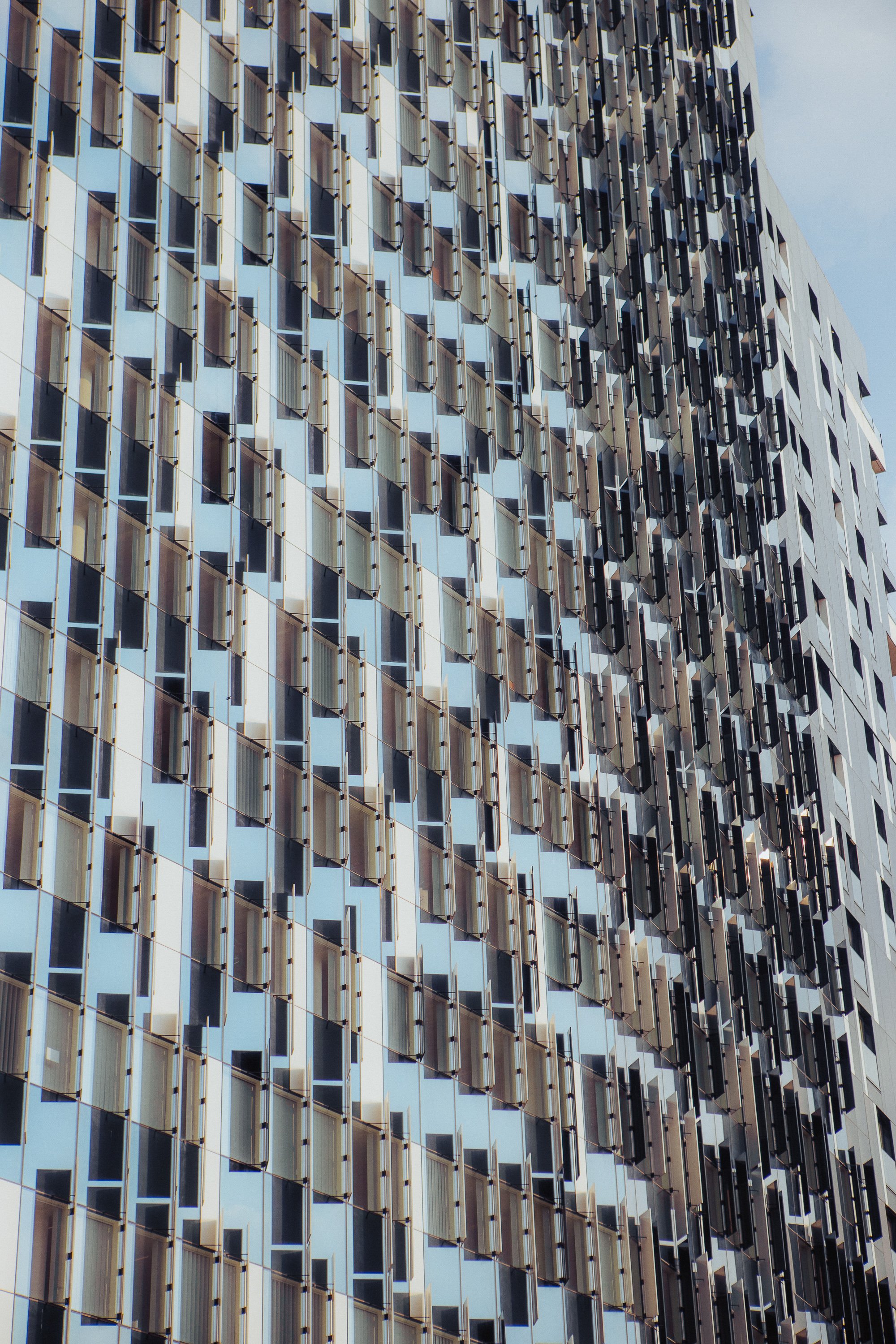 Abstract view of modern building facade with geometric pattern of windows and shades.