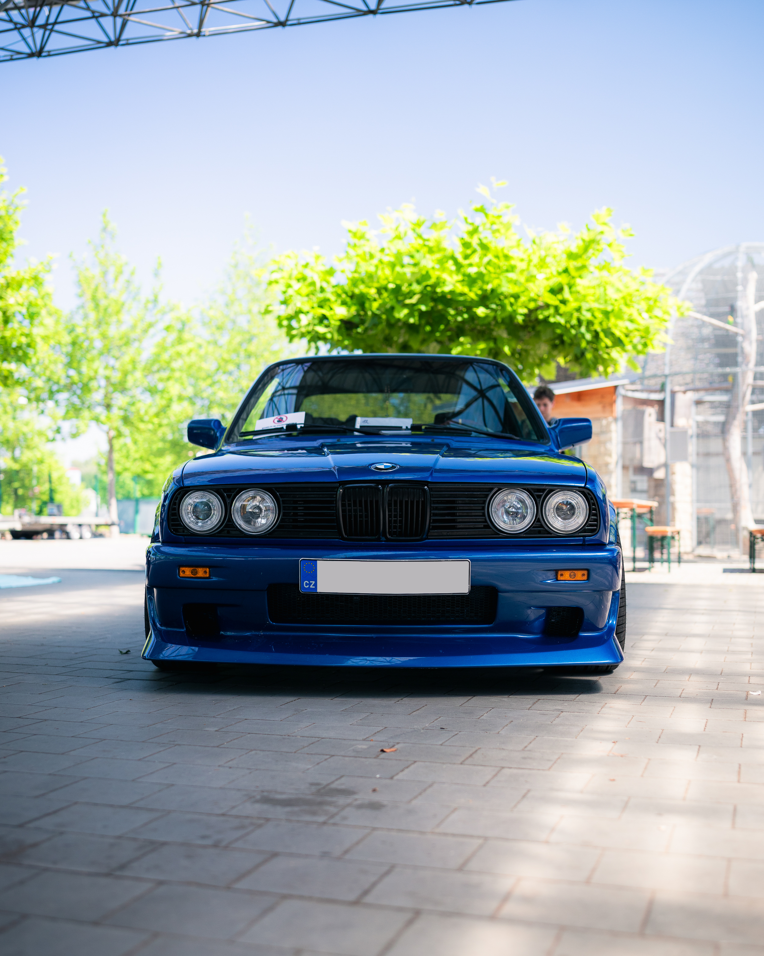 Front view of a blue BMW car parked outdoors on a sunny day.