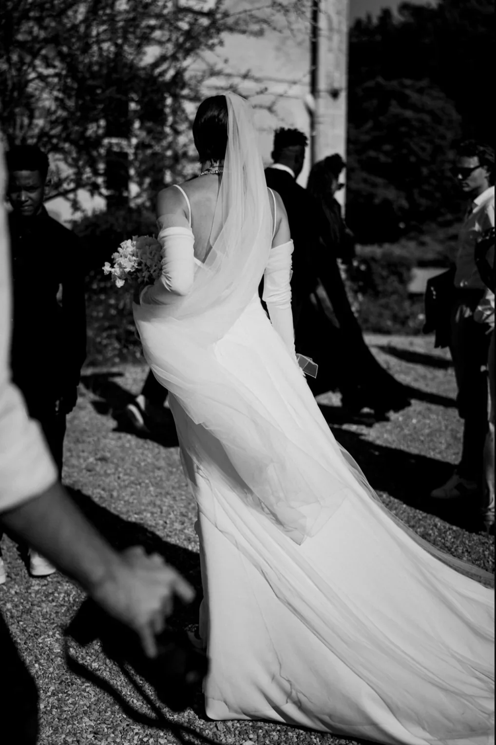 reportage-mariage-mariee-de-dos-robe-traine-voile-cathedrale-noir-blanc-photographe-mariage-film-mariage-the-wild-strawberry.webp