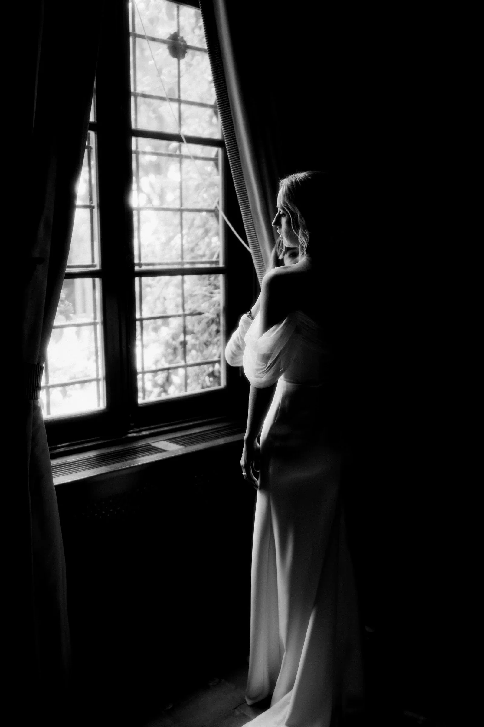 silhouette-mariee-fenetre-lumiere-chateau-photographe-mariage-video-mariage-the-wild-strawberry.webp