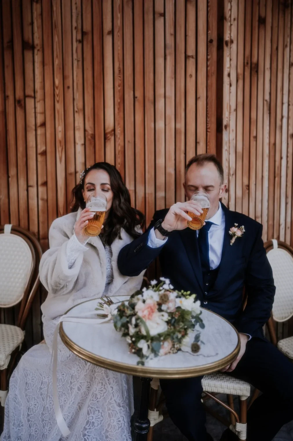 portrait-couple-maries-biere-terrasse-cafe-fun-hiver-photographe-mariage-film-mariage-the-wild-strawberry.webp
