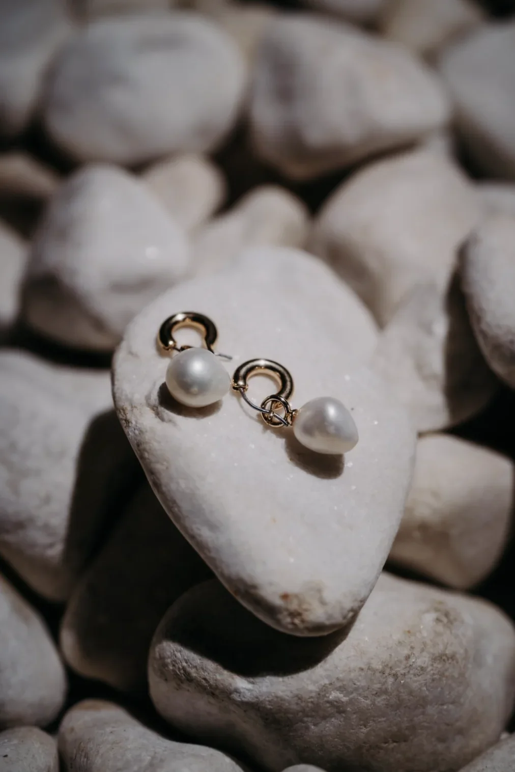 details-bijoux-mariee-boucles-oreilles-perles-galets-photographe-mariage-video-mariage-the-wild-strawberry.webp