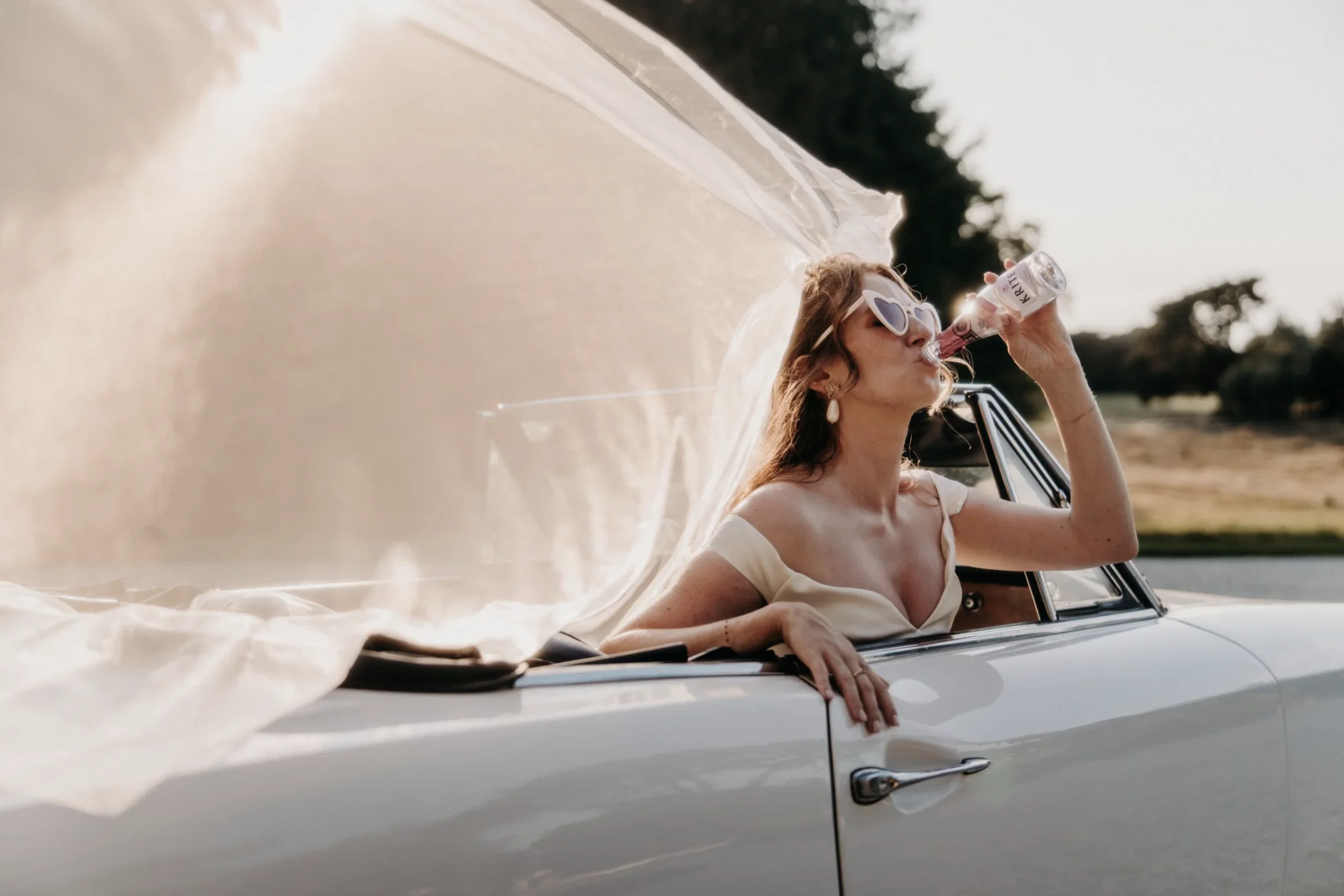 portrait-mariee-voiture-cabriolet-fun-golden-hour-editorial-photographe-mariage-video-mariage-the-wild-strawberry.webp