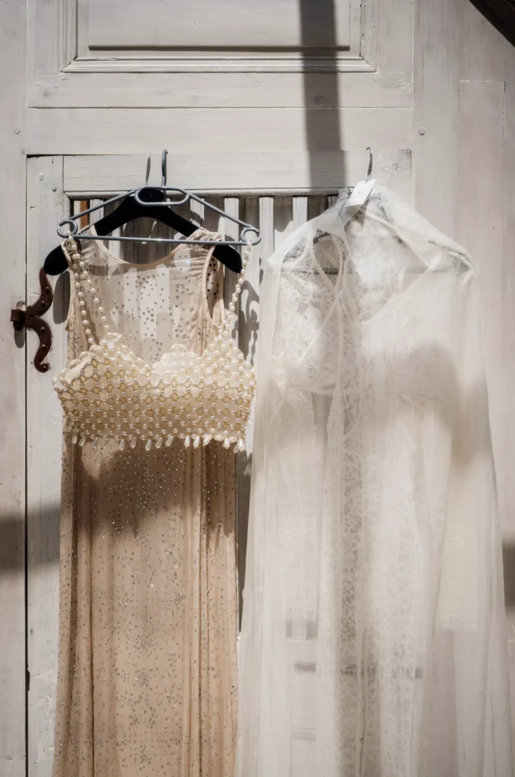 preparatifs-robes-mariee-cintre-lumiere-porte-ancienne-photographe-mariage-film-mariage-the-wild-strawberry.webp