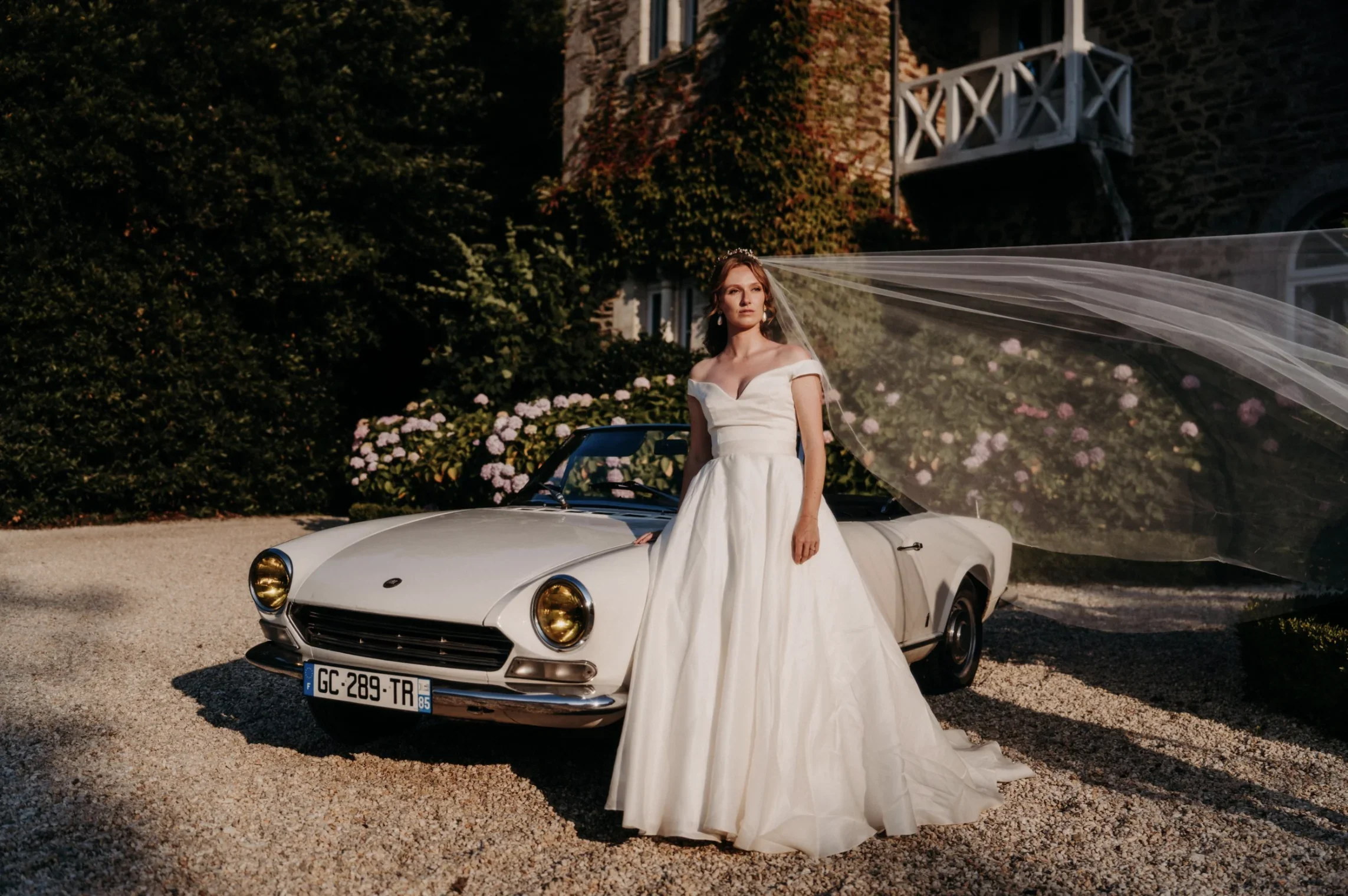 portrait-mariee-robe-princesse-voiture-vintage-cabriolet-chateau-photographe-mariage-film-mariage-the-wild-strawberry.webp