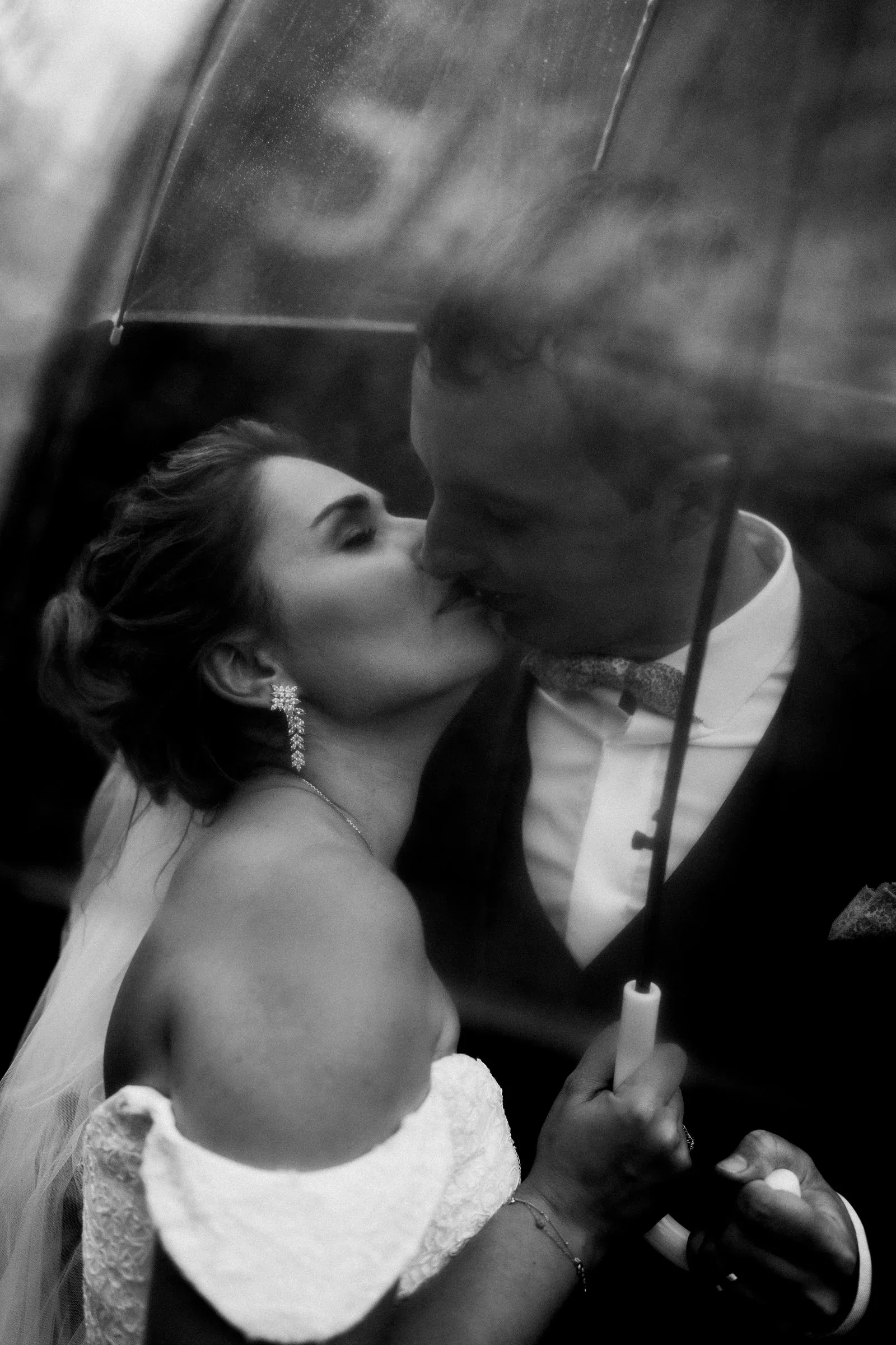 baiser-maries-pluie-parapluie-romantique-photographe-mariage-video-mariage-the-wild-strawberry.webp