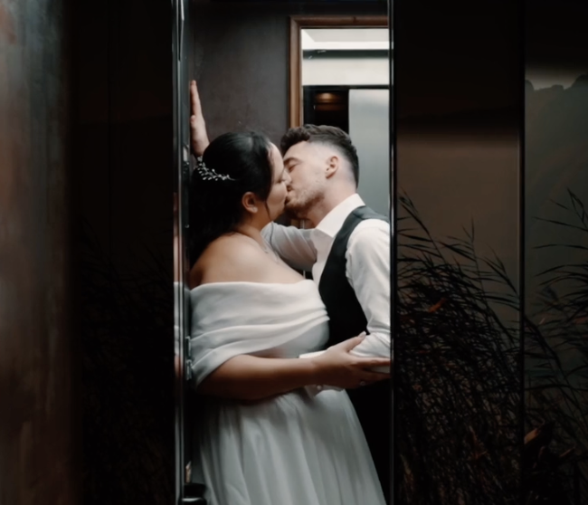 Un couple habillé pour un mariage s'embrasse dans un ascenseur.