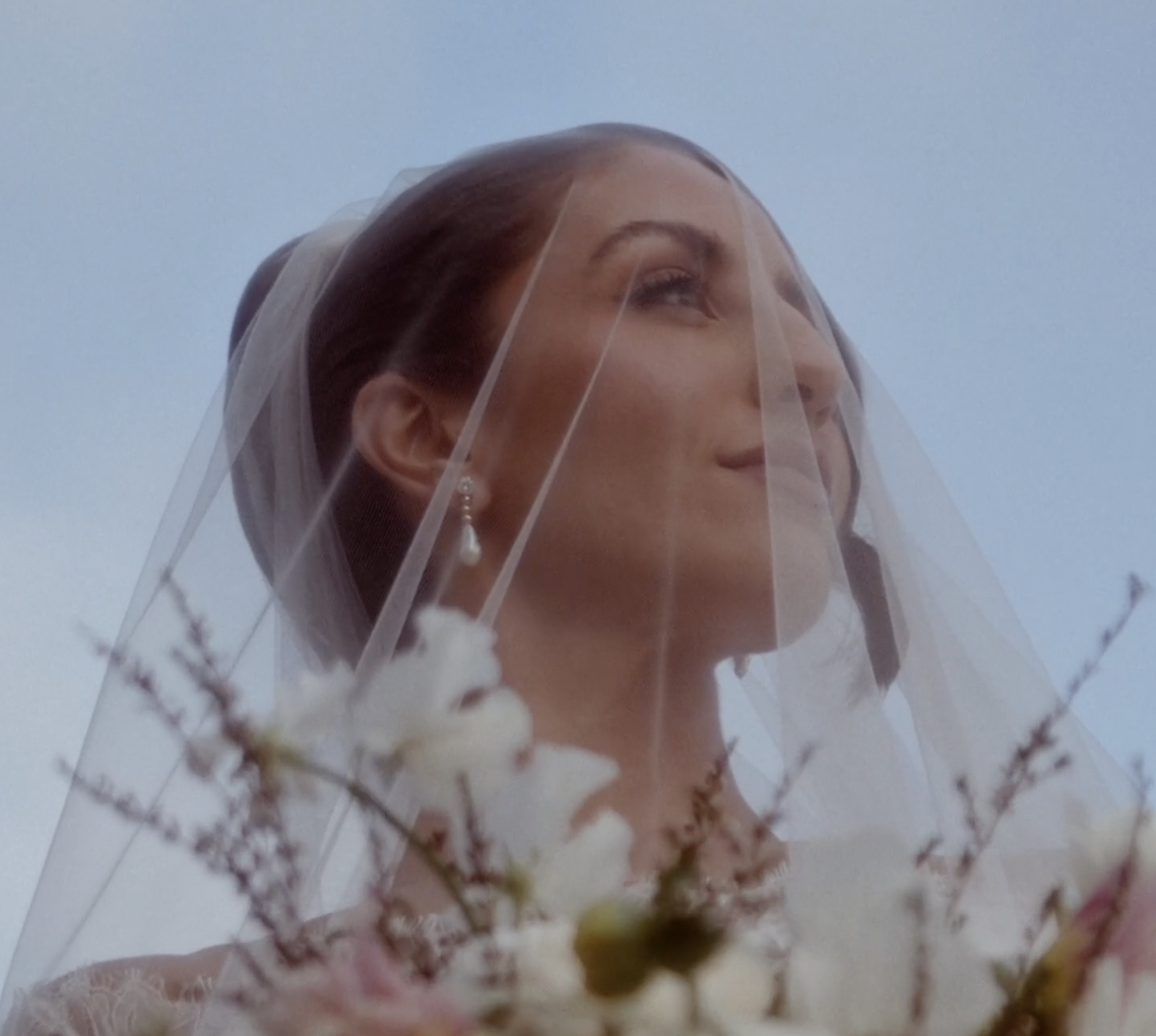 Une femme portant un voile en regardant vers le haut, avec des fleurs au premier plan.