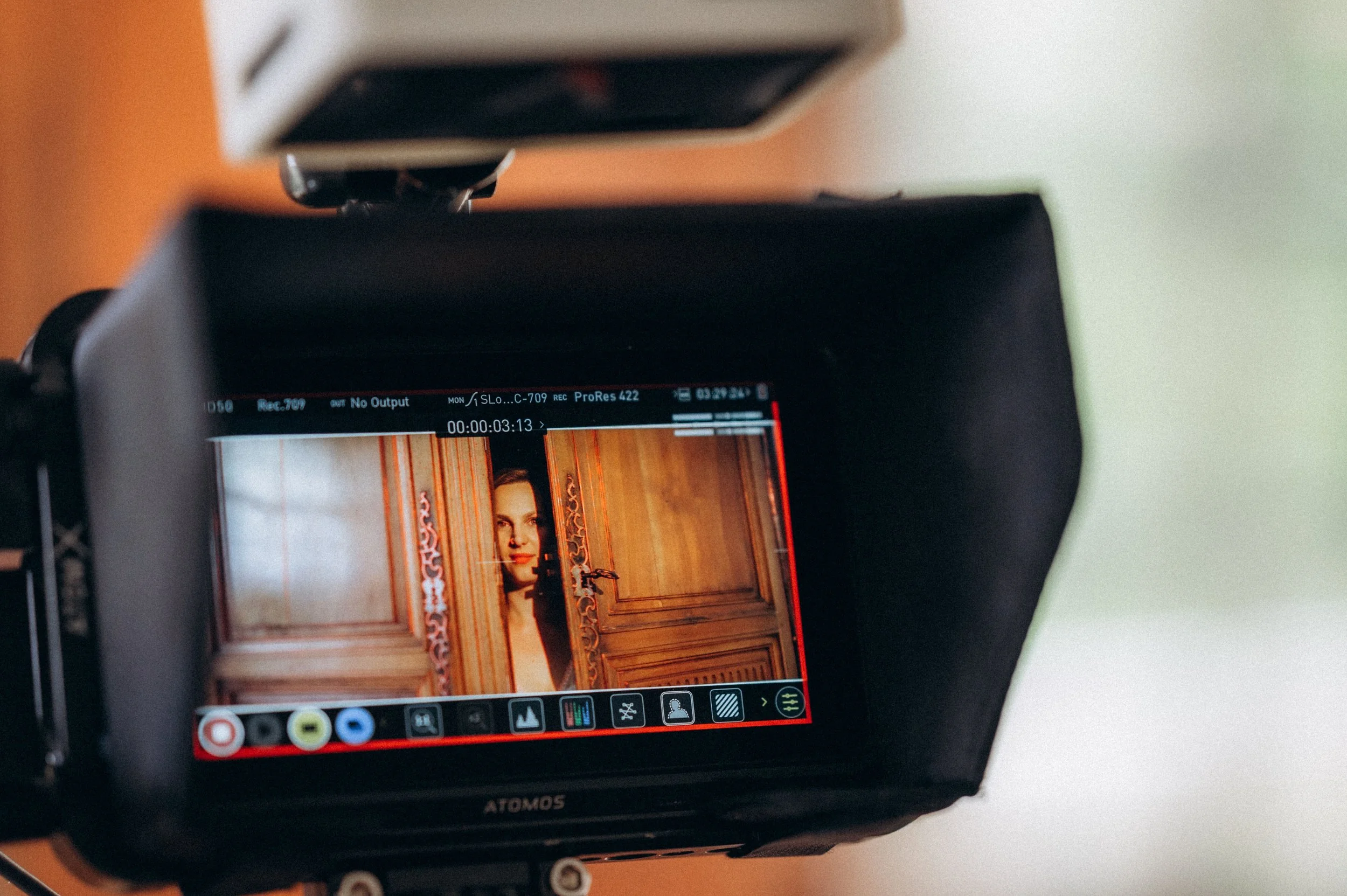 Capture d'écran d'une caméra vidéo montrant une femme regardant à travers une porte en bois ornée.